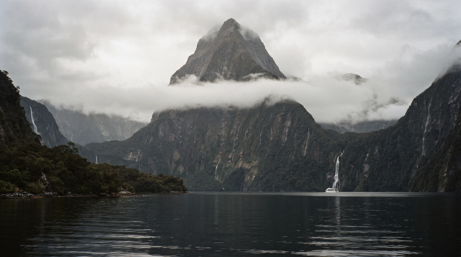 Mitre Peak rising above the water with a cruise boat below it on a Milford Sound day trip from Queenstown, New Zealand