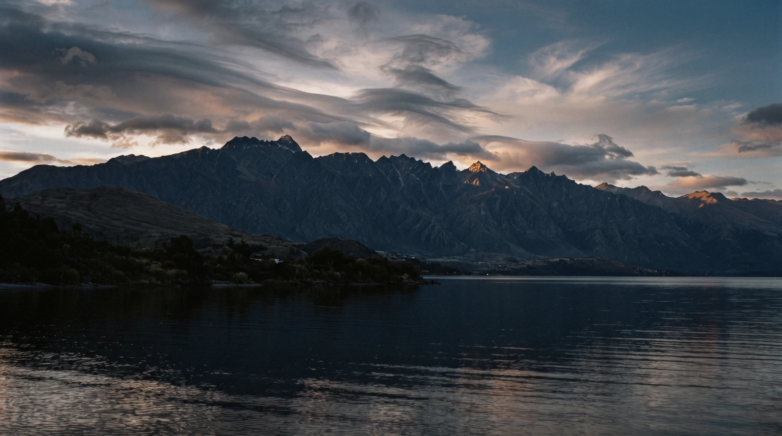 The saw-tooth wall of The Remarkables range above Lake Wakatipu at last light seen from Queenstown, New Zealand