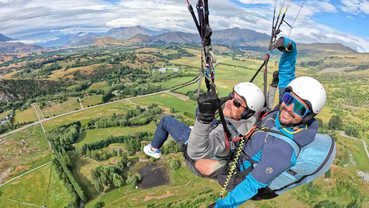 A tandem paraglider turning above the Wakatipu Basin — paragliding in Queenstown, New Zealand